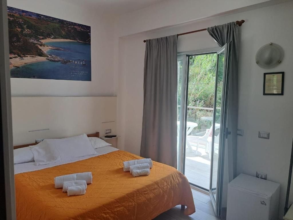 Habitación de hotel con cama, ventana, vista al exterior y un cuadro colgado en la pared.