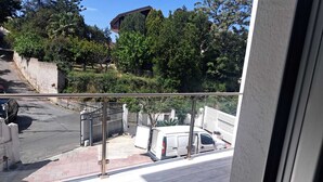 Un balcón con vista a una calle, un coche aparcado y un edificio al fondo.