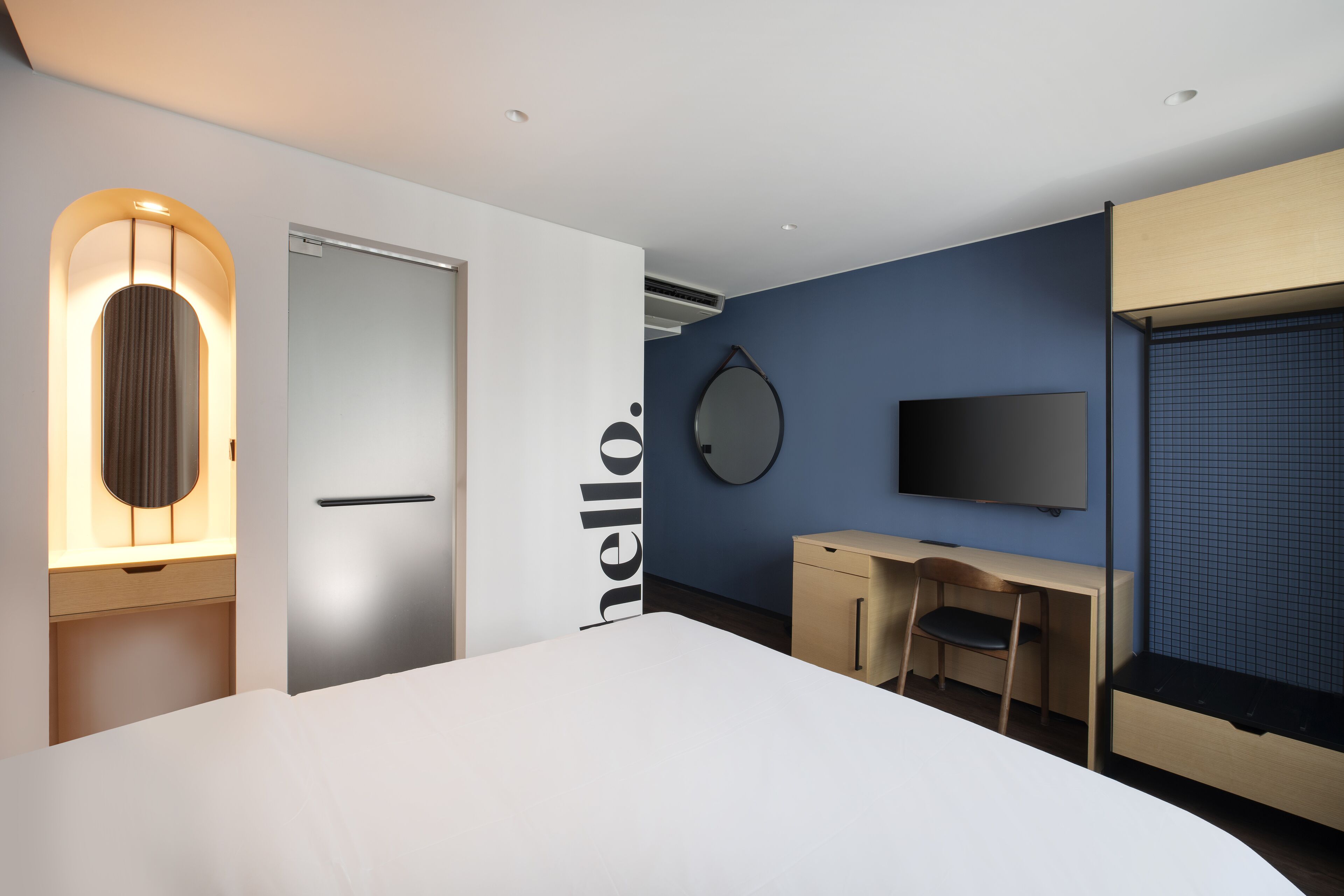 Une chambre d’hôtel moderne équipée d’un grand lit, d’un bureau, d’une chaise, d’une télévision et d’un miroir.