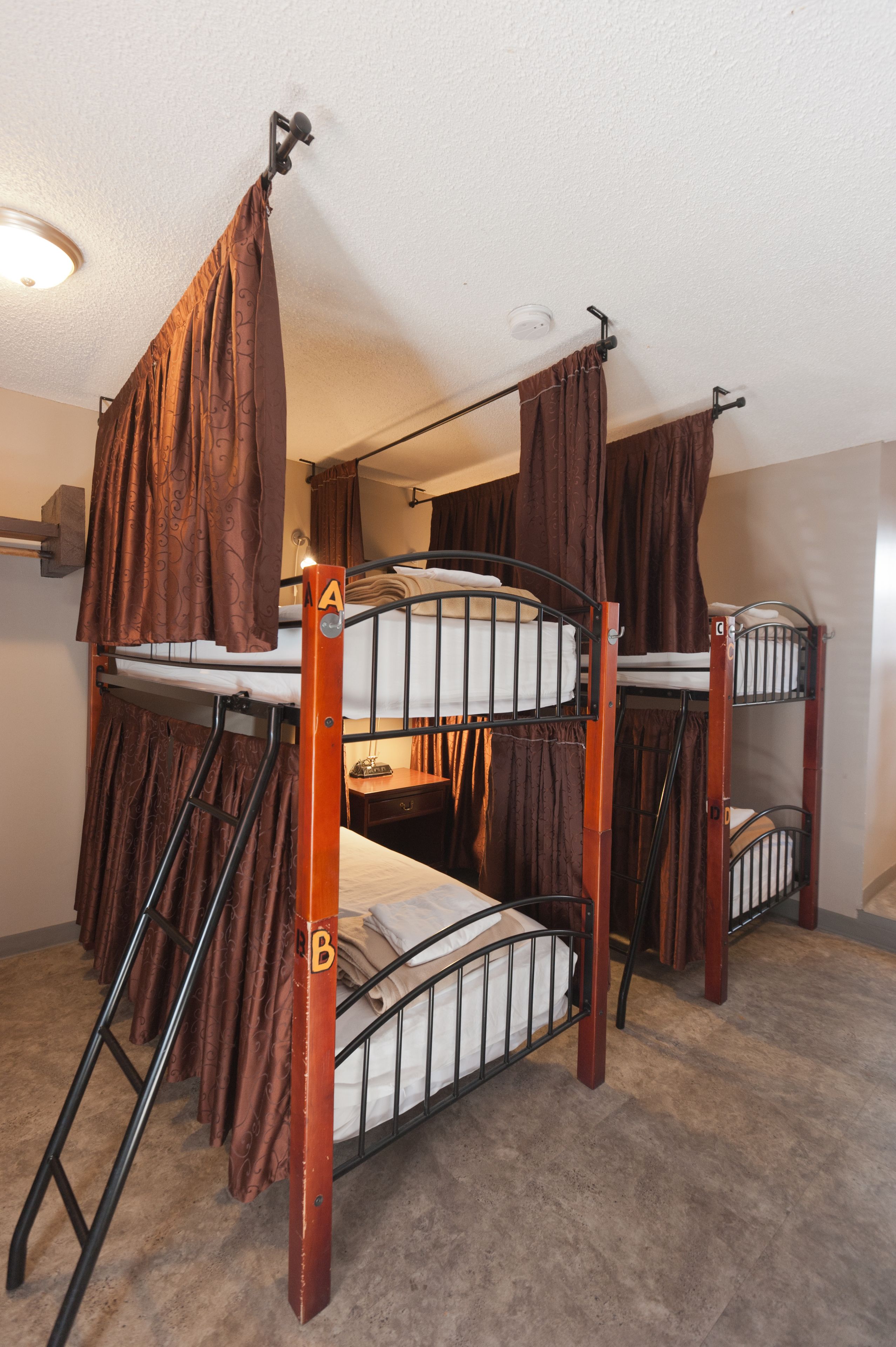 A bunk bed room with two levels, a ladder, and curtains.