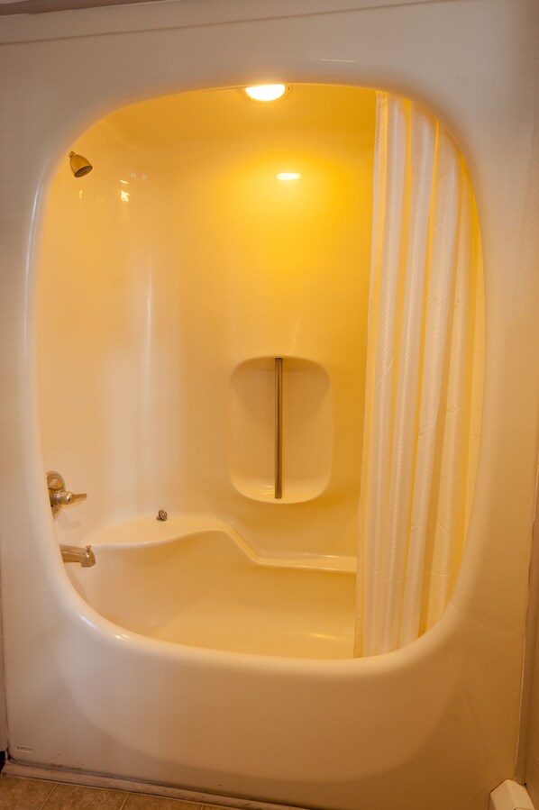 A bathtub with a showerhead, a towel rack, and a curtain.