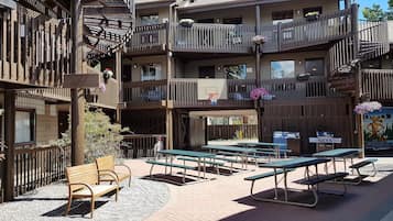 Un edificio de varios pisos con balcones, mobiliario exterior y un aro de baloncesto.