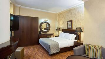 A hotel room with a bed, a TV, a desk, a chair, and a lamp.