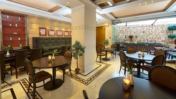 A hotel lobby with a bar area, seating arrangements, and a stone wall.