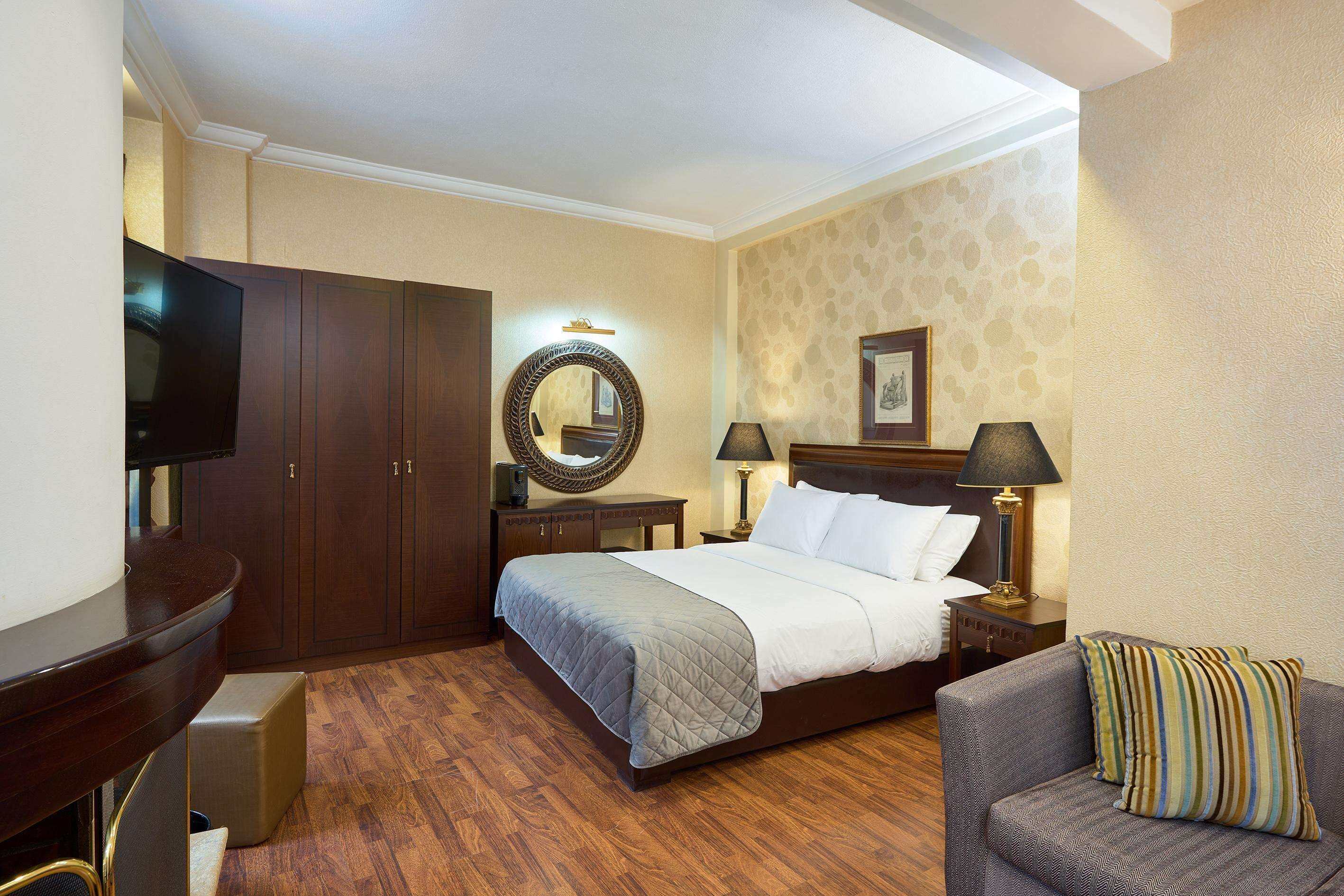 A hotel room with a large bed, a TV, a desk, and a sofa.