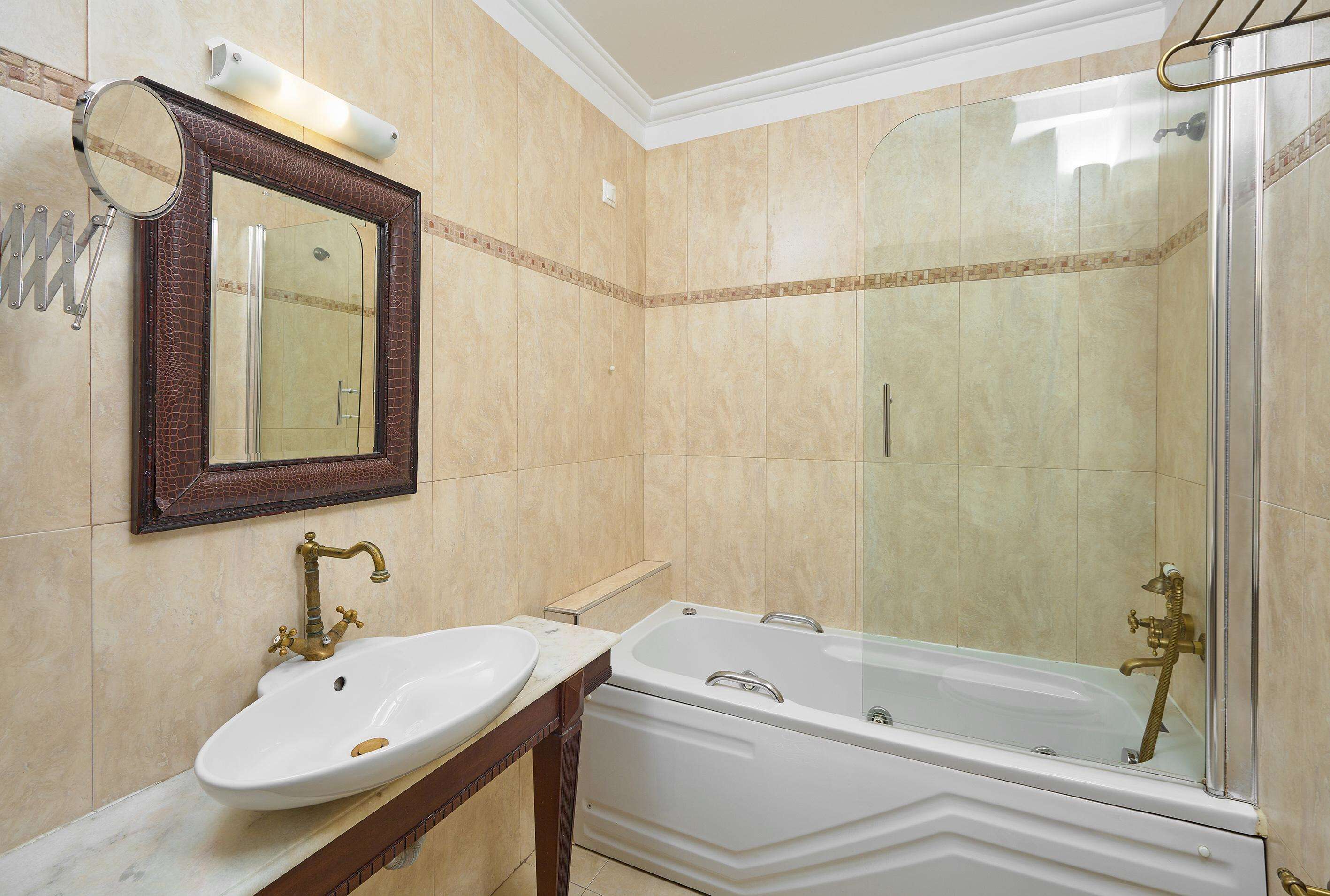 A bathroom with a sink, mirror, and bathtub.