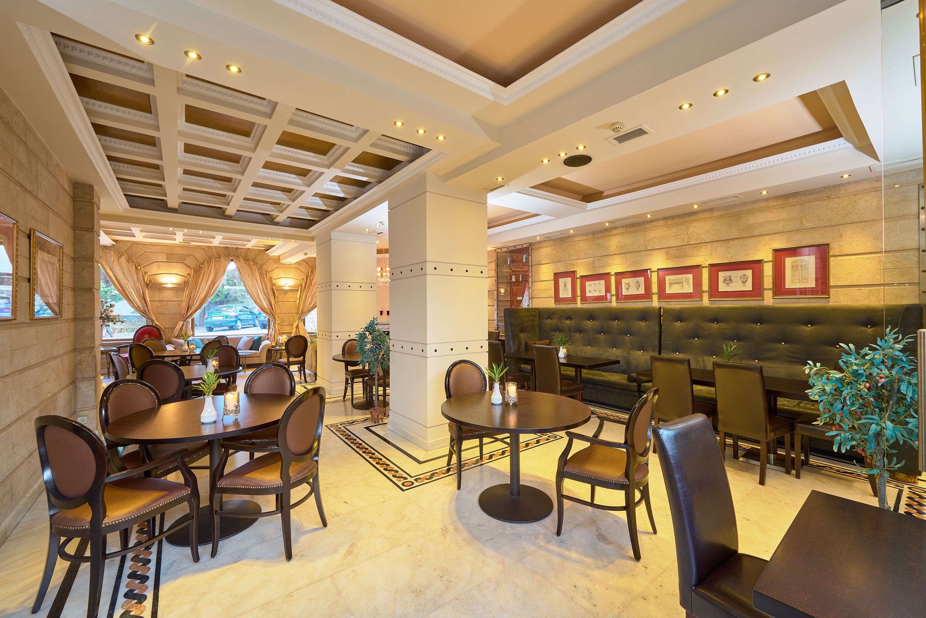 A restaurant with a high ceiling, chandeliers, and a view of the city.