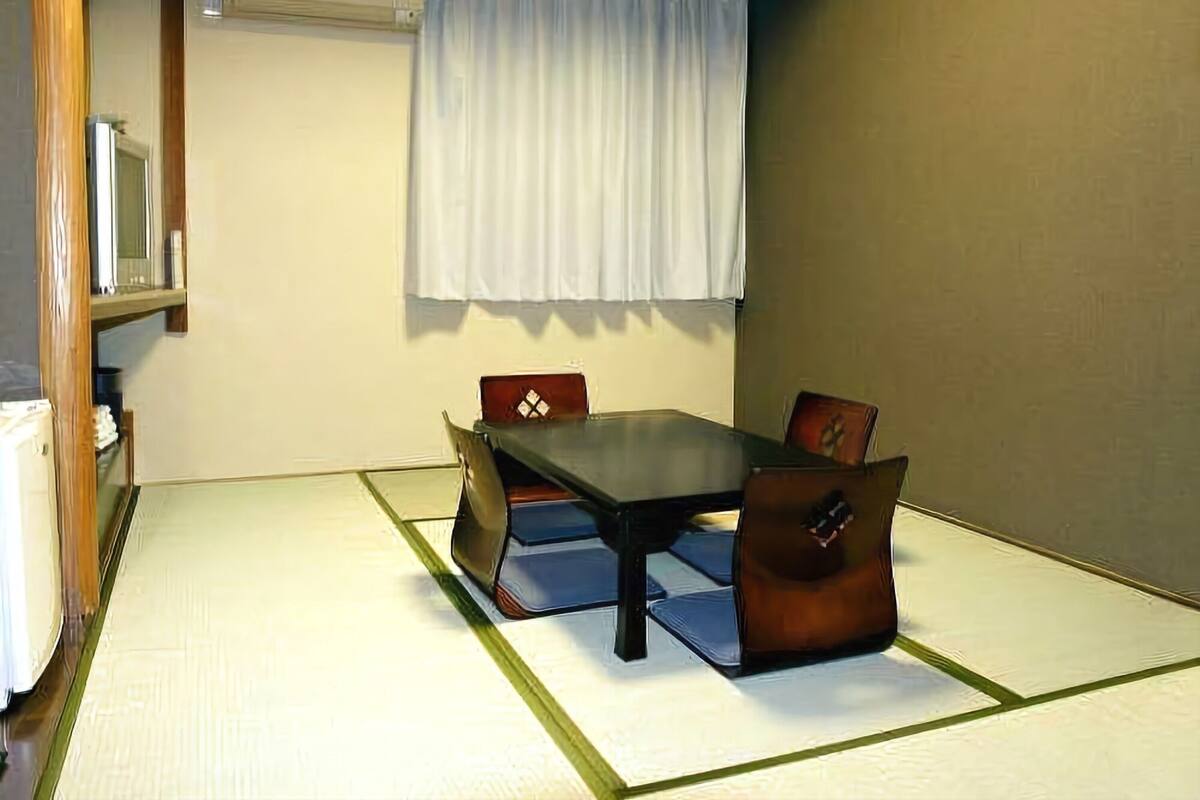 A traditional Japanese room with tatami flooring, a low table, and cushions.