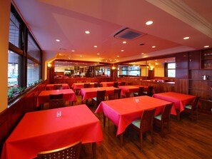 A restaurant with multiple tables covered in red tablecloths, wooden chairs, and a bar area in the background. - Hotel Asyl Nara Annex (Nara)