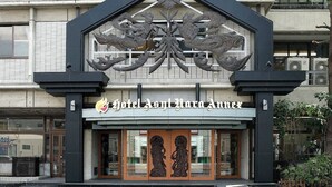 A hotel entrance with a distinctive black and white facade, featuring a large decorative metal crest above the entrance. - Hotel Asyl Nara Annex (Nara)