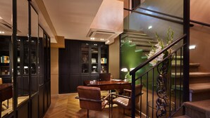 Een modern interieur met een houten vloer, een bureau met stoel, een trap met leuning en een groene accentmuur.