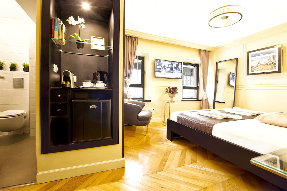 Een hotelkamer met een bed, bureau, stoel, televisie en een badkamer.