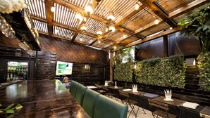 Een restaurant met een houten inrichting, een lange toonbank en groene bekleding.