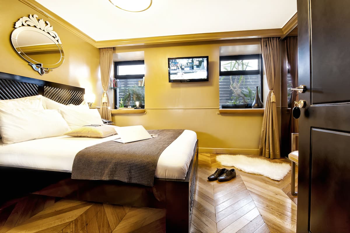 Een hotelkamer met een bed, een televisie, een spiegel en een raam met gordijnen.