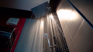 Ducha con chorros de agua, un perchero y una pared roja.