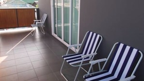 Un balcón con dos sillones a rayas y vista a un edificio de techo verde.