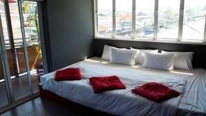Una habitación de hotel con una cama grande, ropa de cama blanca y almohadas rojas.