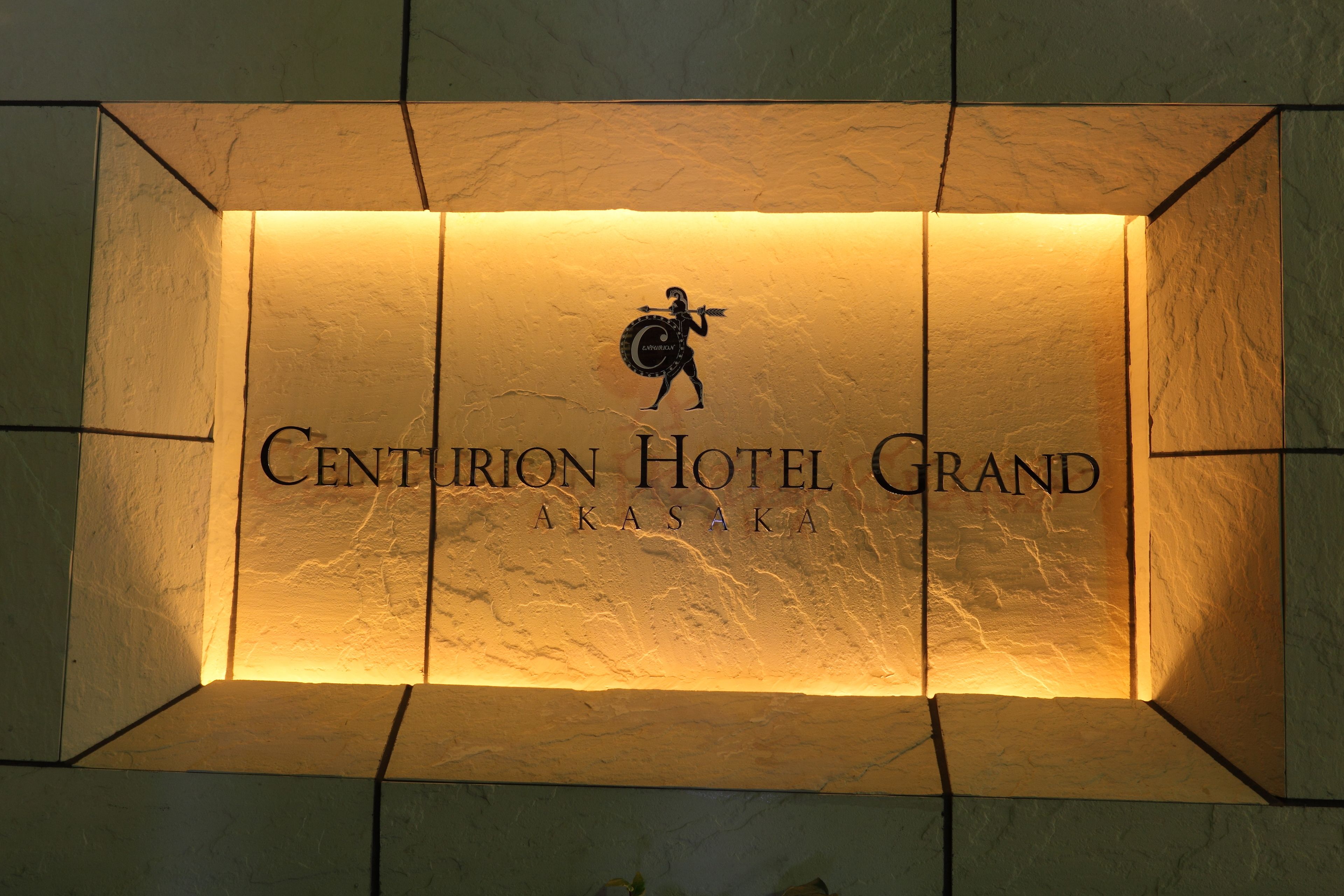 A sign for Centurion Hotel Grand in Asaka with a silhouette of a person holding a shield.