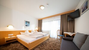 Une chambre d’hôtel avec un lit, un canapé, un bureau et une télévision.