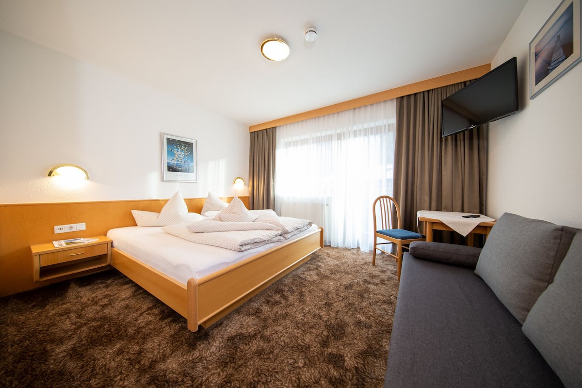 Ein Hotelzimmer mit Bett, Sofa, Schreibtisch und Fernseher.