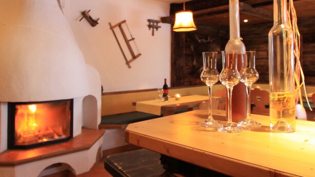 Un restaurant à l’ambiance chaleureuse, avec un poêle à bois, des tables en bois et des verres à vin.