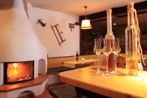 Een gezellig restaurantinterieur met een houtkachel, houten tafels en wijnglazen.