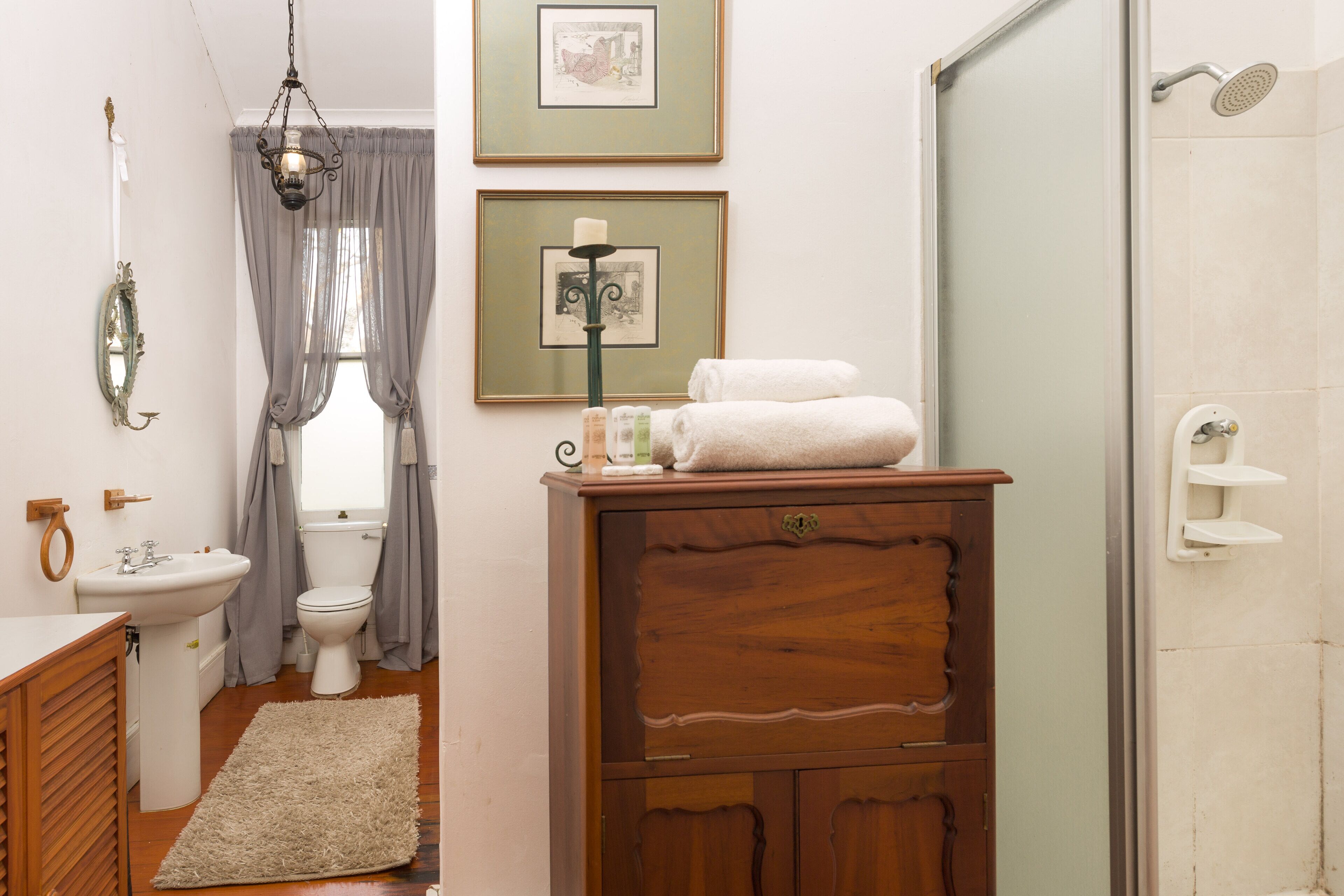 A bathroom with a wooden cabinet, a sink, a toilet, and a shower.