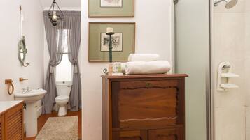 A bathroom with a wooden cabinet, a sink, a toilet, and a shower.