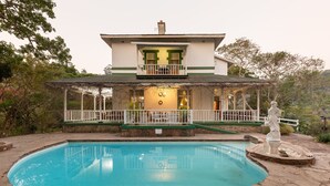 A two-story house with a swimming pool, a covered patio, and a statue. - Royston Hall Guesthouse (Port Shepstone)