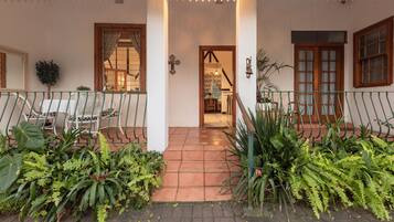A covered outdoor area with a tiled floor, a wooden door, and a staircase leading inside.