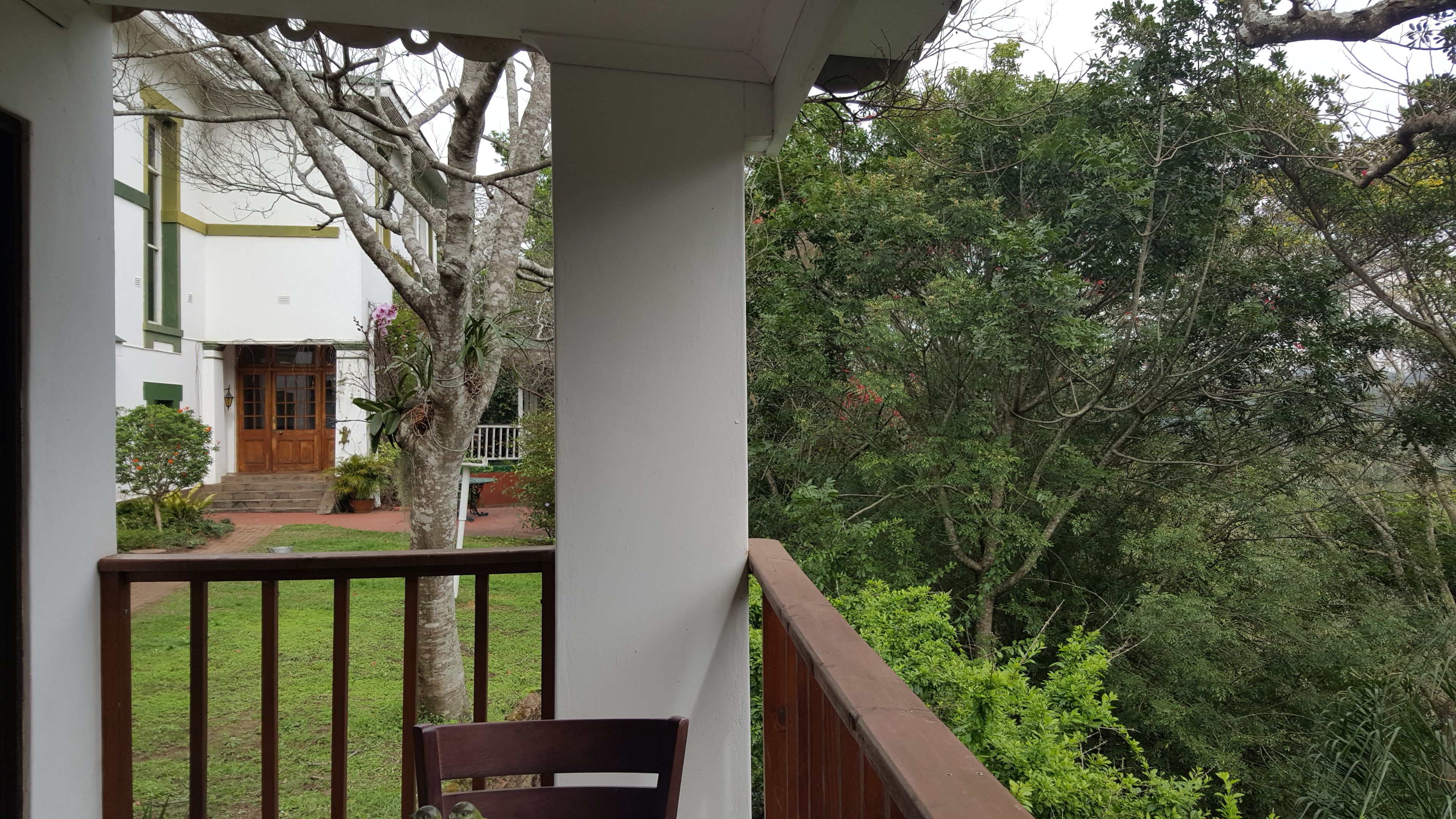A balcony with a view of a house and dense greenery.