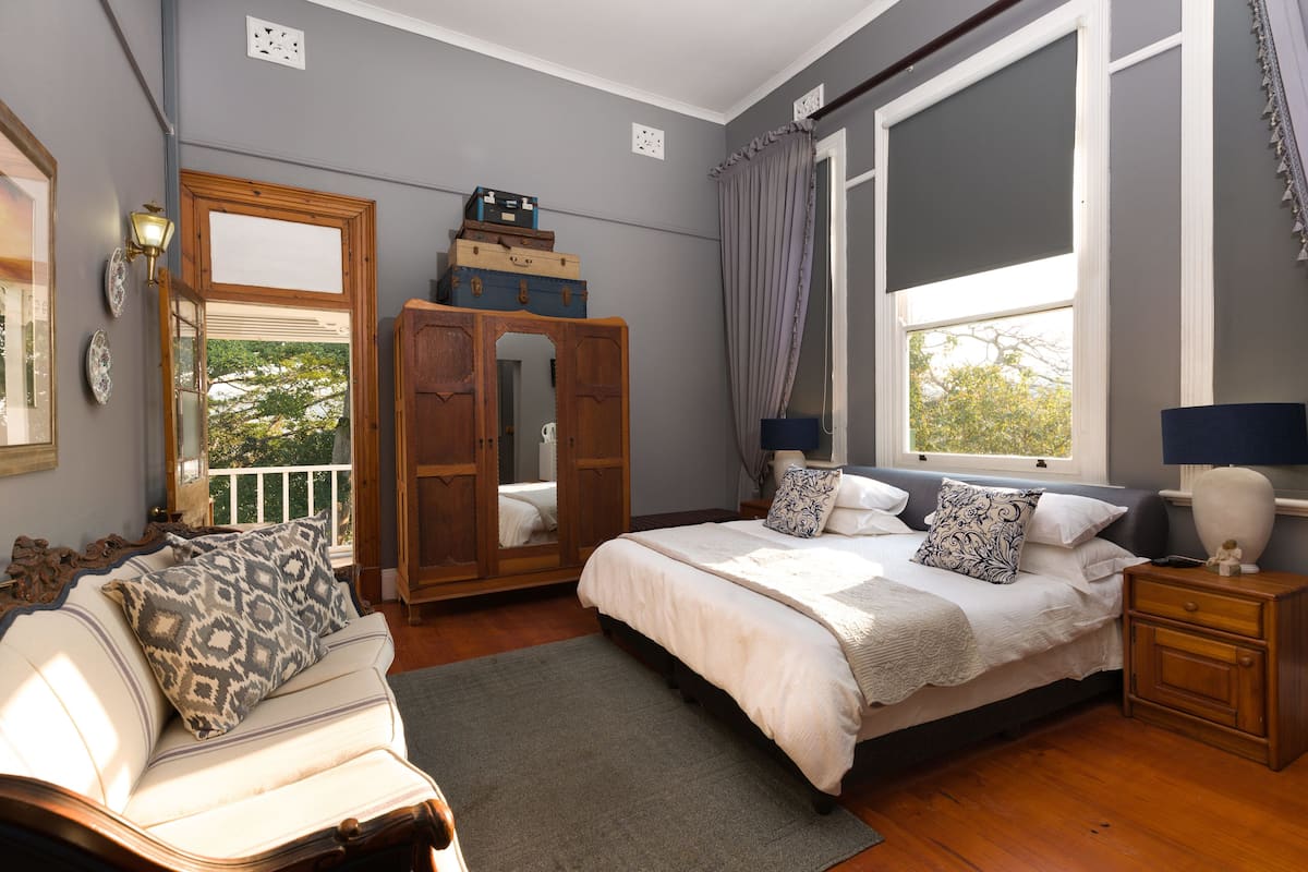 Un dormitorio con una cama grande, un armario de madera, un espejo y una ventana con cortinas.
