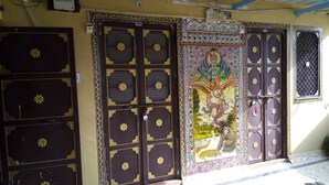 Une façade d’immeuble ornée de portes richement décorées et d’une fresque représentant une divinité.