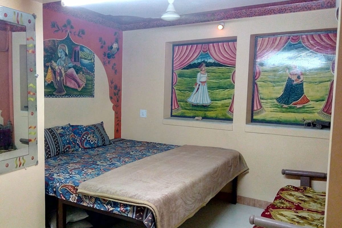 Une chambre à coucher avec un lit, un miroir et deux tableaux accrochés au mur.