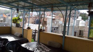 Un espace extérieur abrité, aménagé pour s’asseoir, et offrant une vue sur le paysage urbain.