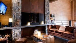 Una sala de estar acogedora con chimenea de piedra, televisión de pantalla plana y asientos cómodos.