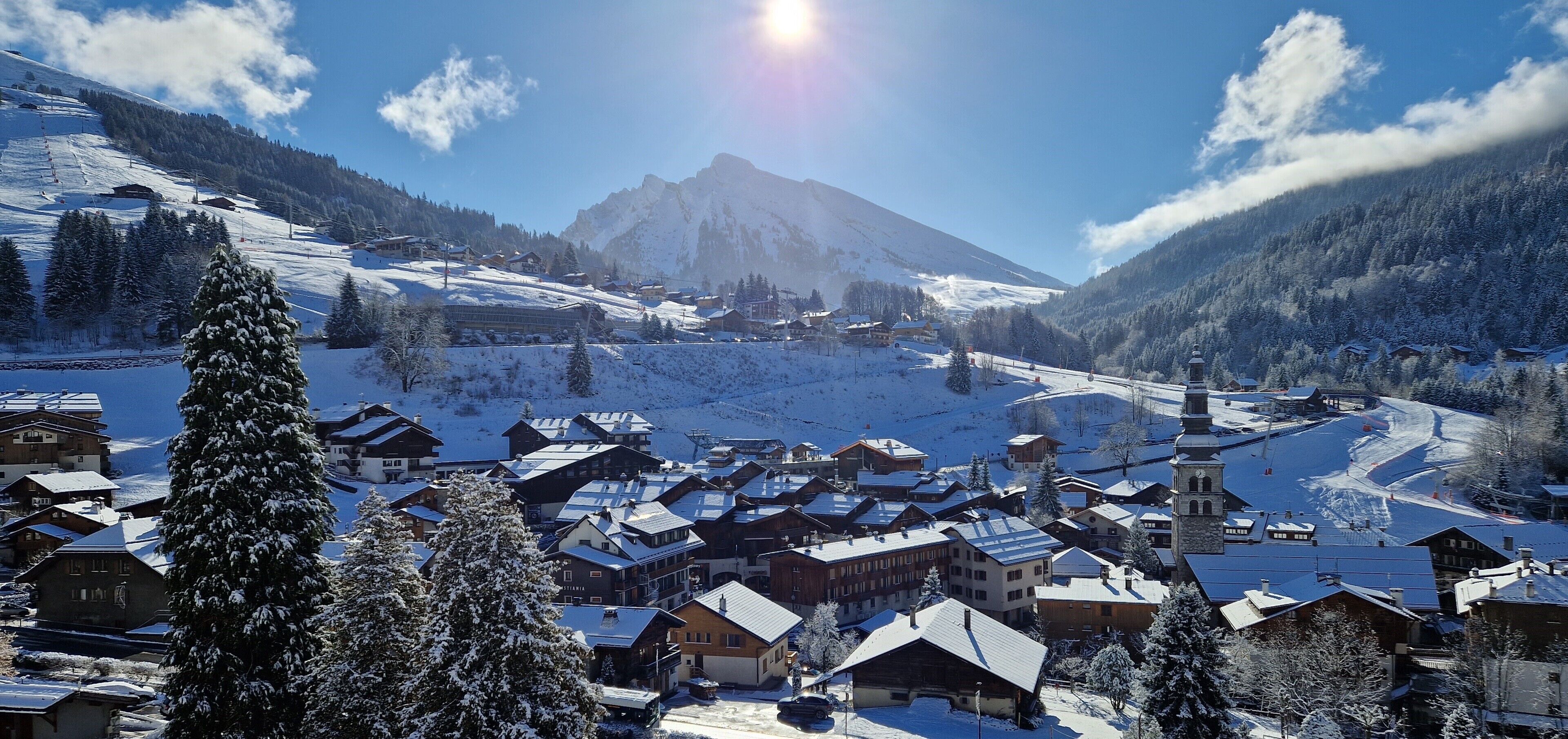 A snow-covered village with traditional wooden houses, a church, and a mountain in the background.