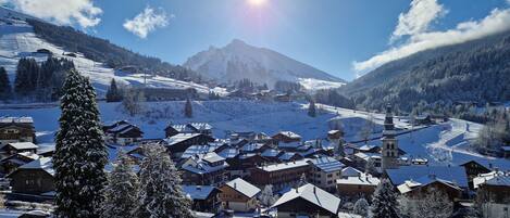 A snow-covered village with traditional wooden houses, a church, and a mountain in the background.