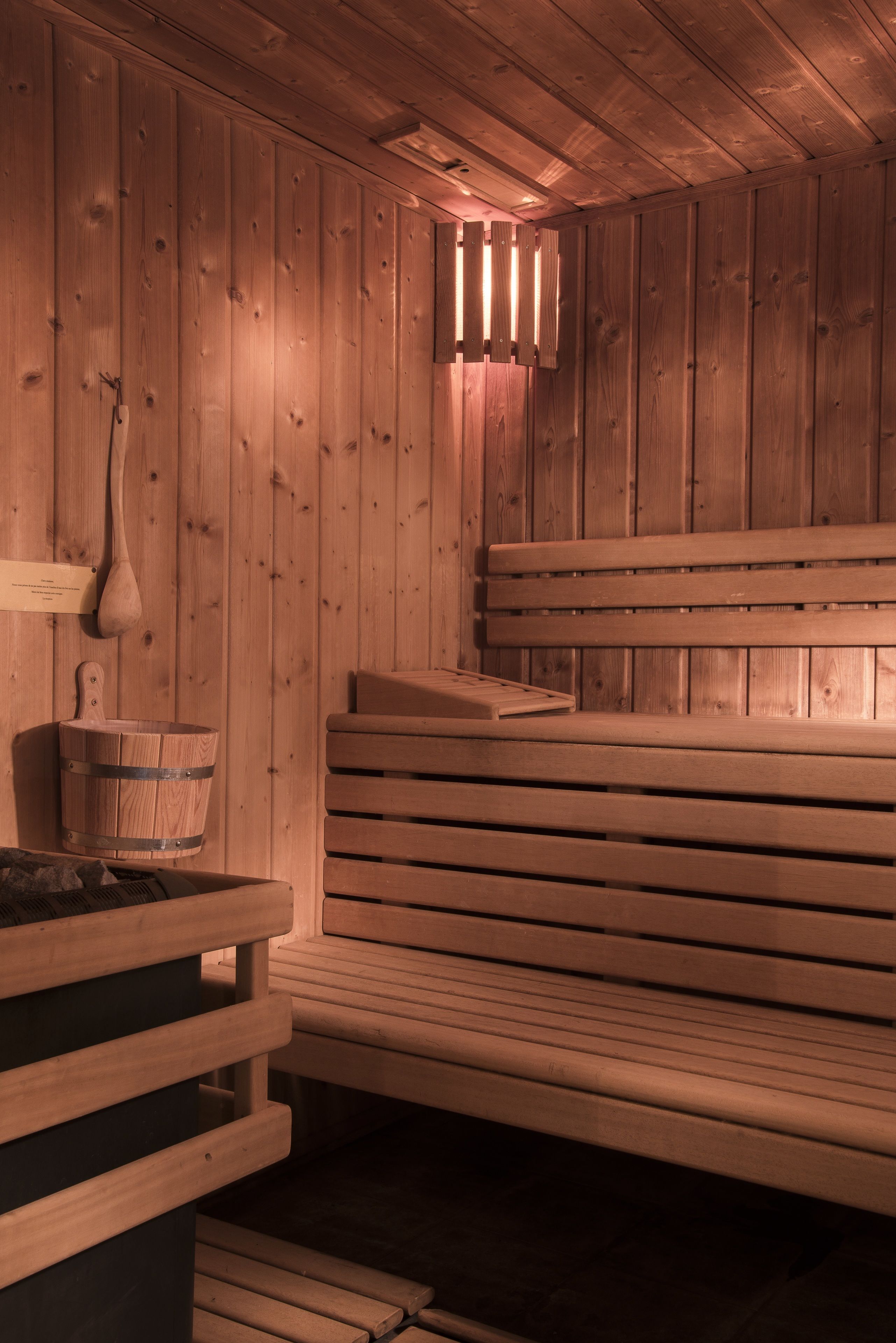 A wooden sauna with benches and a wooden bucket.