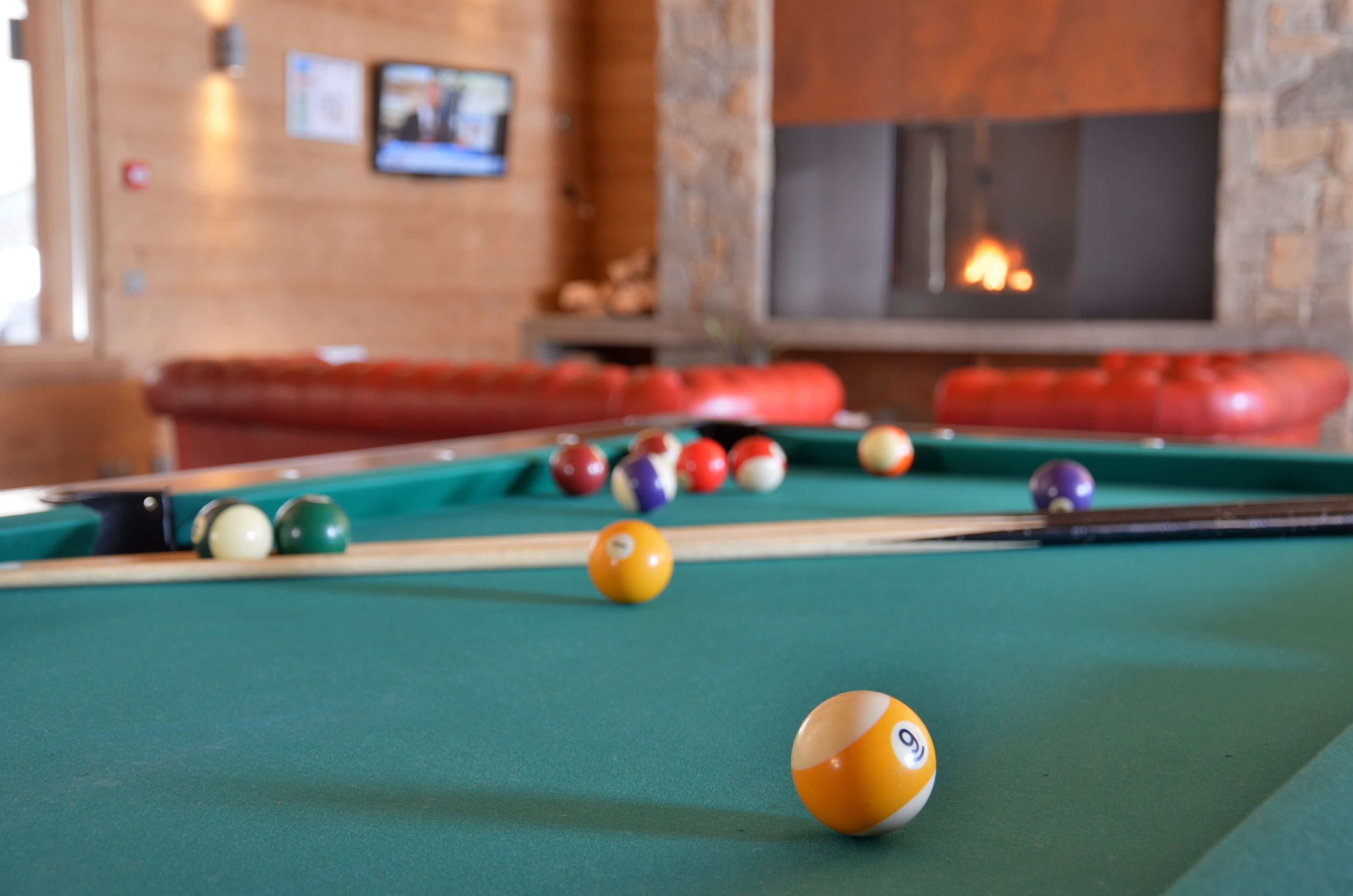 A pool table with balls in a room with a fireplace and a stone wall.
