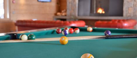 A pool table with balls in a room with a fireplace and a stone wall.