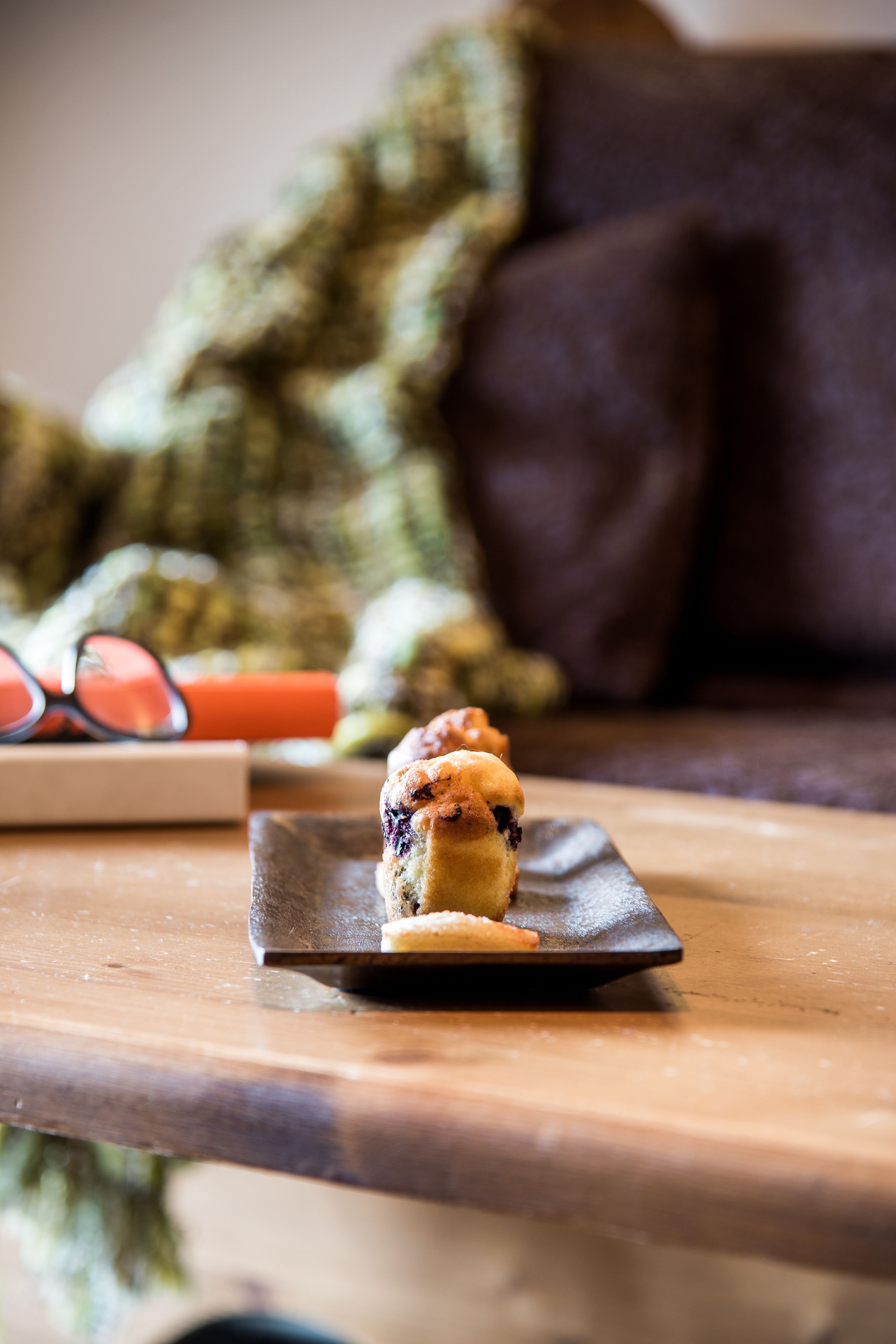 A dessert on a plate on a wooden table with a book and glasses in the background.