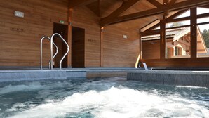 Un spa de madera con un jacuzzi, barandillas de metal y vistas al exterior.
