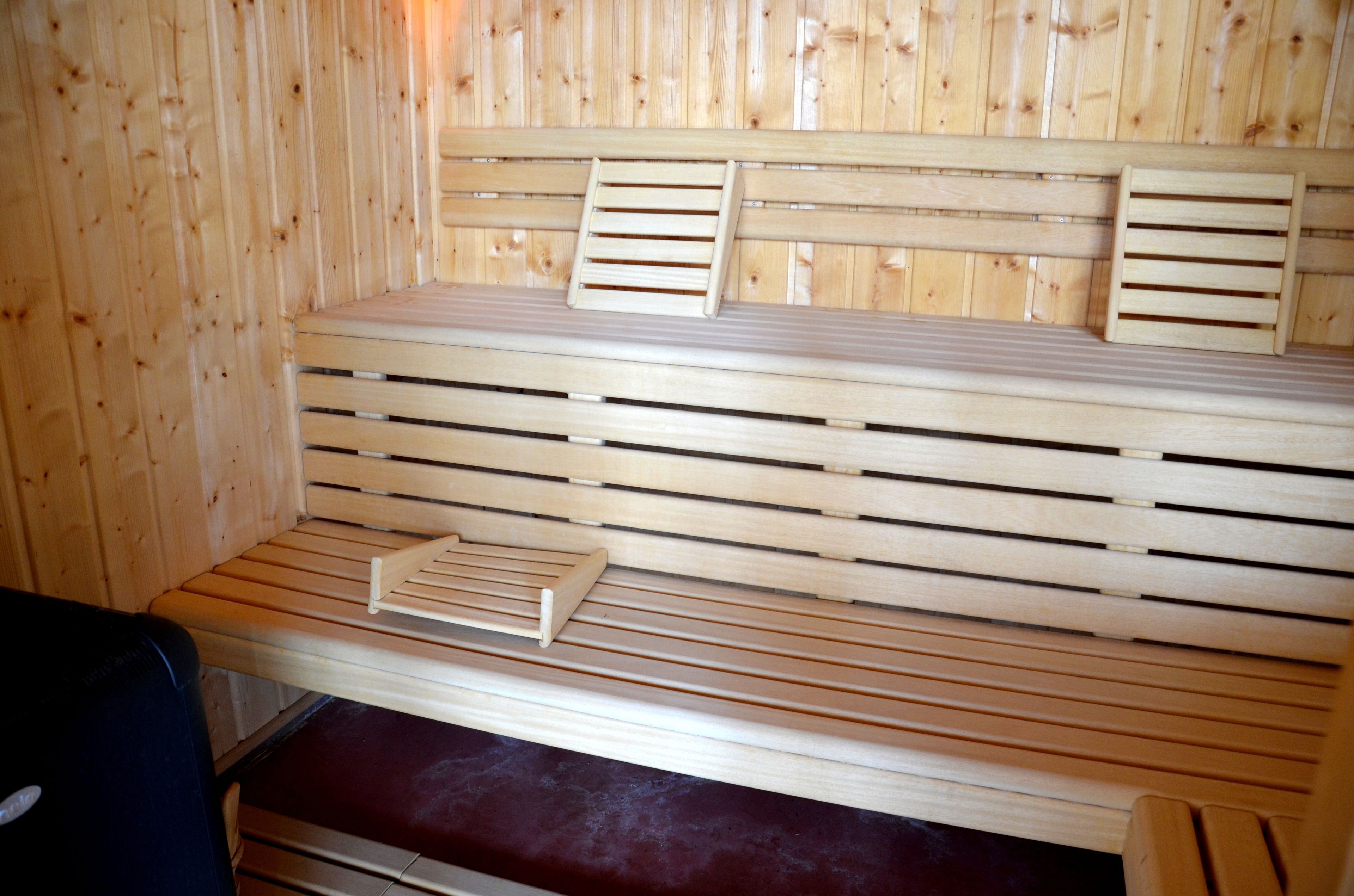 Banco de madera para sauna con asientos de listones y un banco inferior.