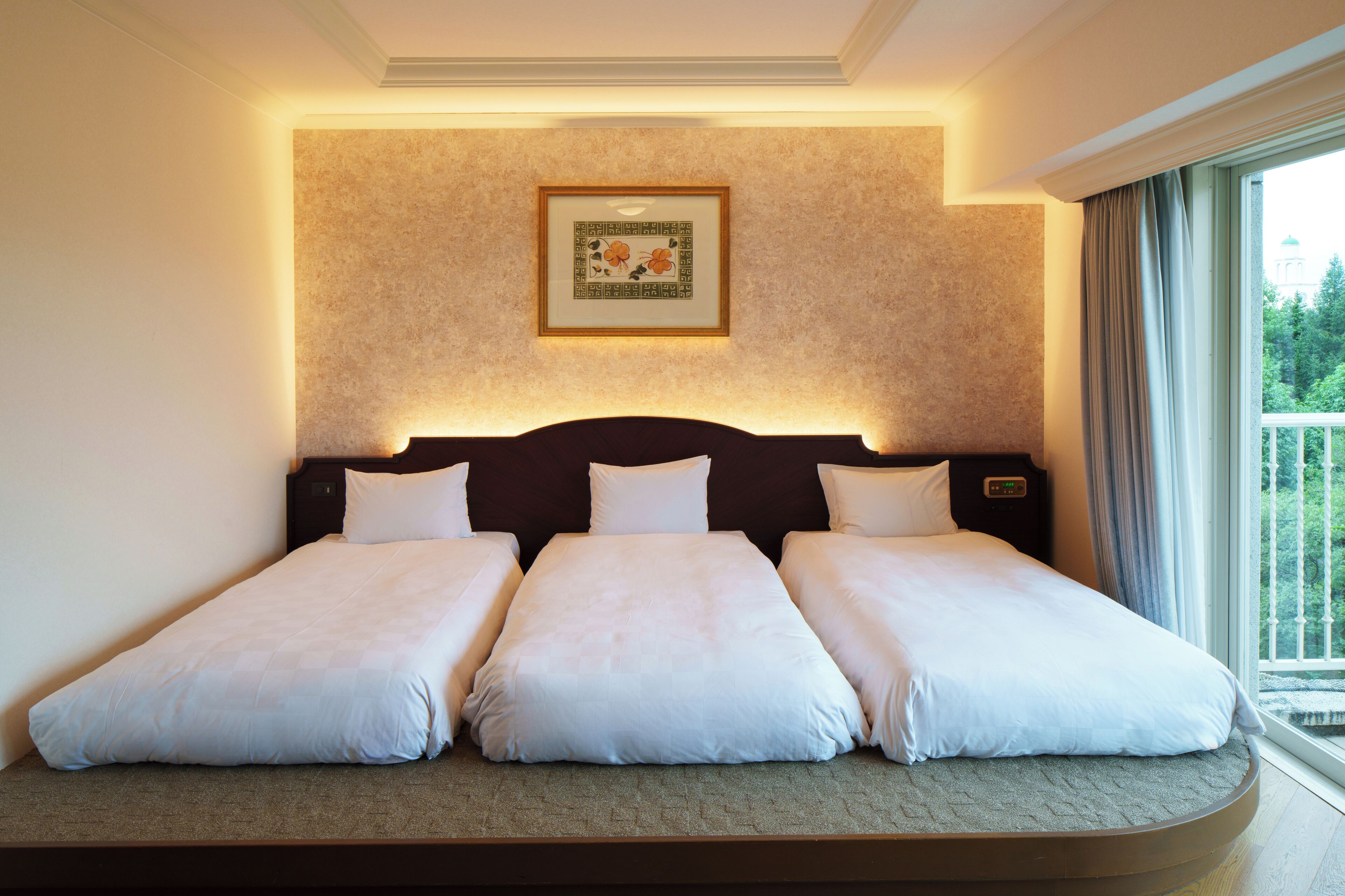 Une chambre d’hôtel avec un grand lit, un tableau encadré au mur et une fenêtre avec des rideaux.