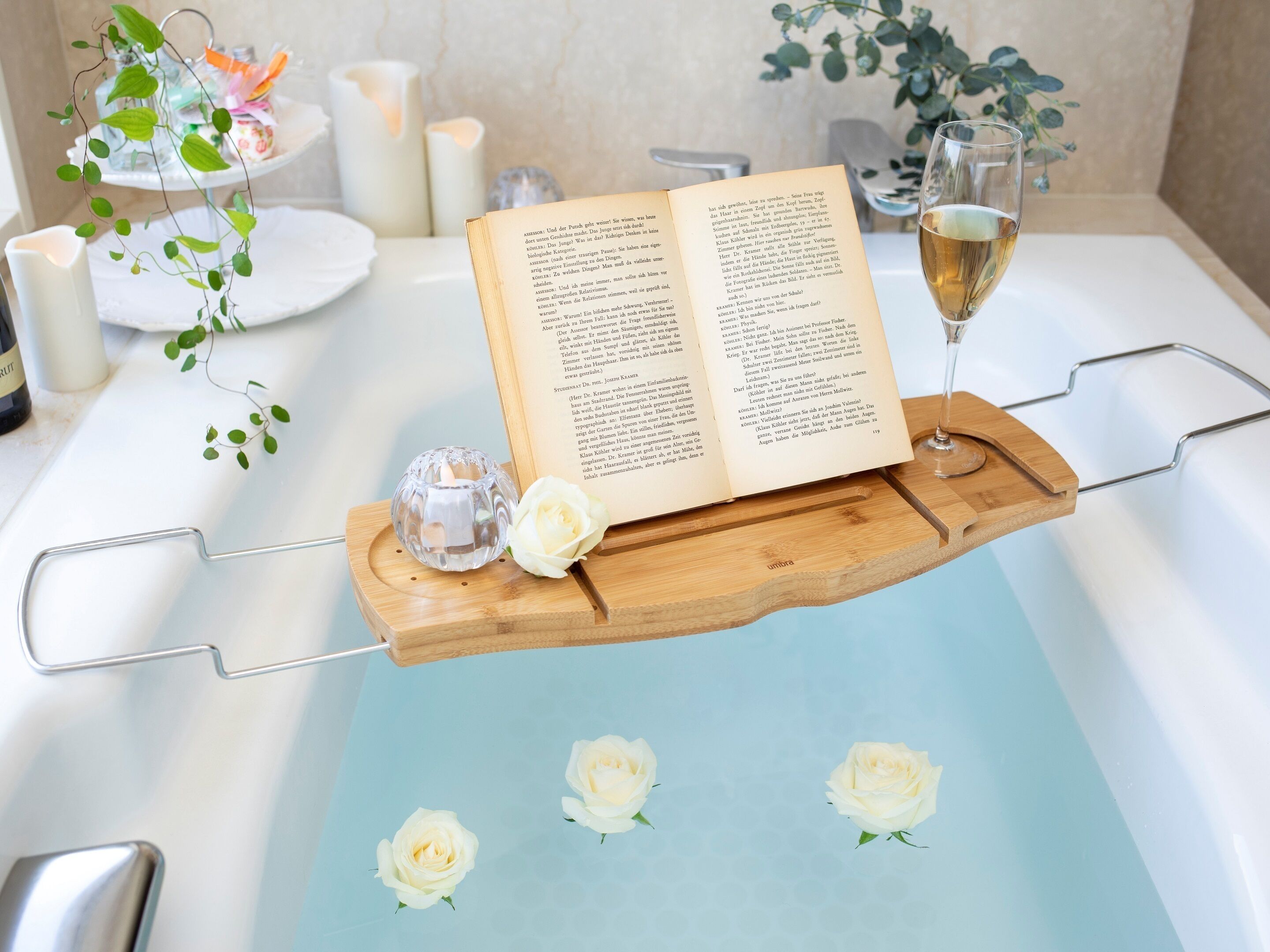 Une baignoire avec un plateau en bois sur lequel repose un livre ouvert et un verre de vin.