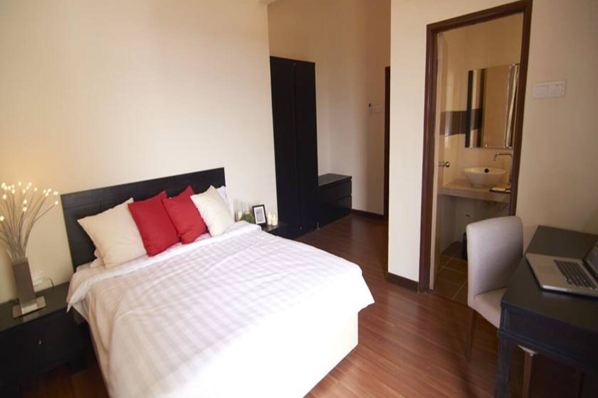 Une chambre d’hôtel avec un lit, un bureau avec un ordinateur portable, un miroir et une salle de bain avec un lavabo.