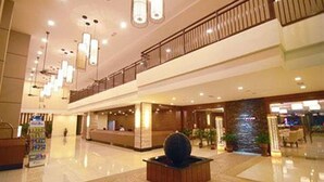 Eine geräumige Lobby mit einer Rezeption, einem dekorativen Brunnen und einem Balkon im zweiten Stock.