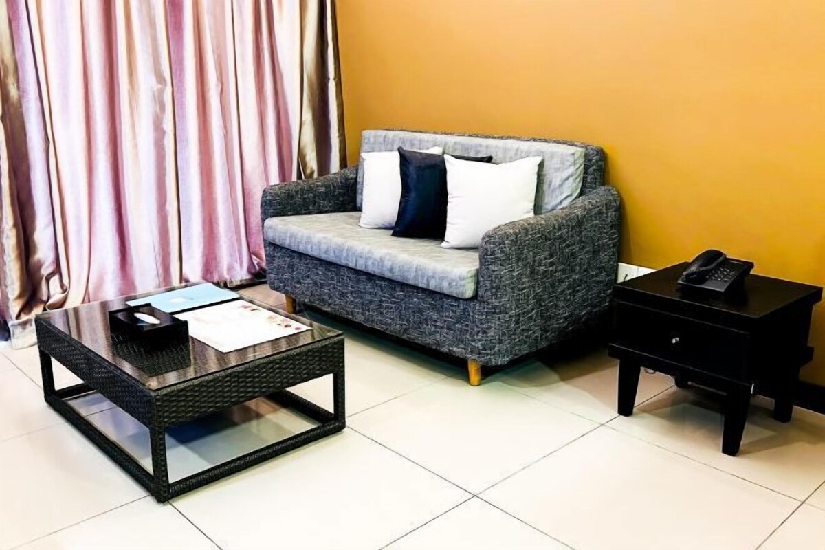 Un espace de vie comprenant un canapé gris, une table basse noire et une table d’appoint noire.