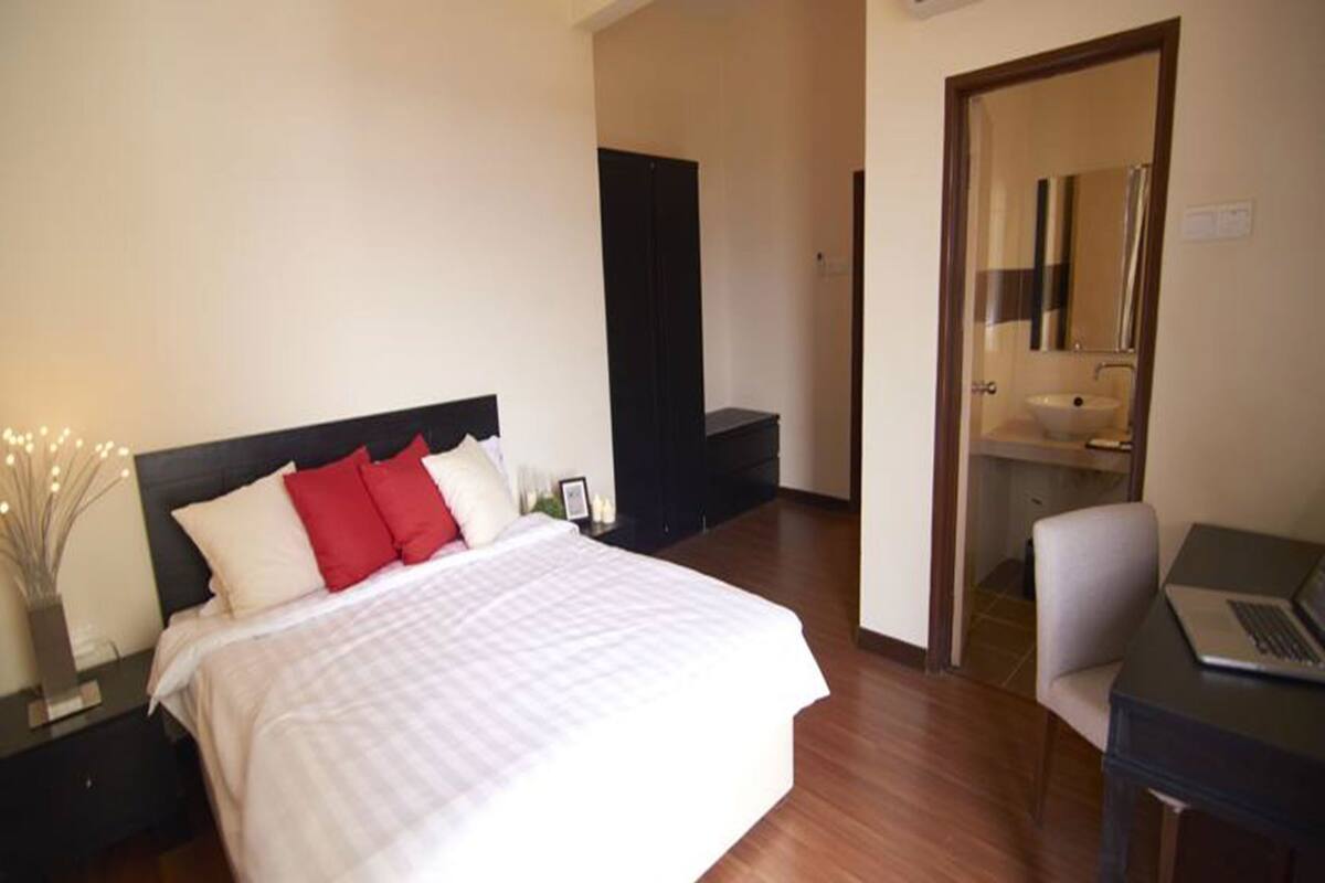 Une chambre d’hôtel comprenant un lit, un bureau avec un ordinateur portable, une salle de bain avec un lavabo et une porte donnant sur une autre pièce.